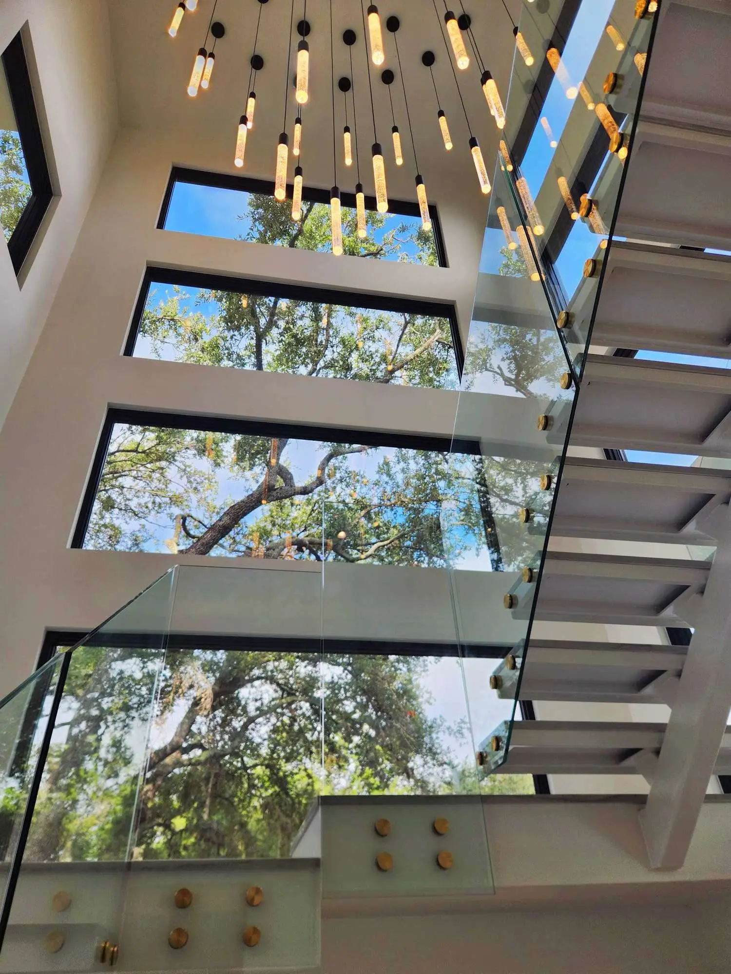 Glass-tread floating staircase with a skylight installed by Marble Falls Glass.
