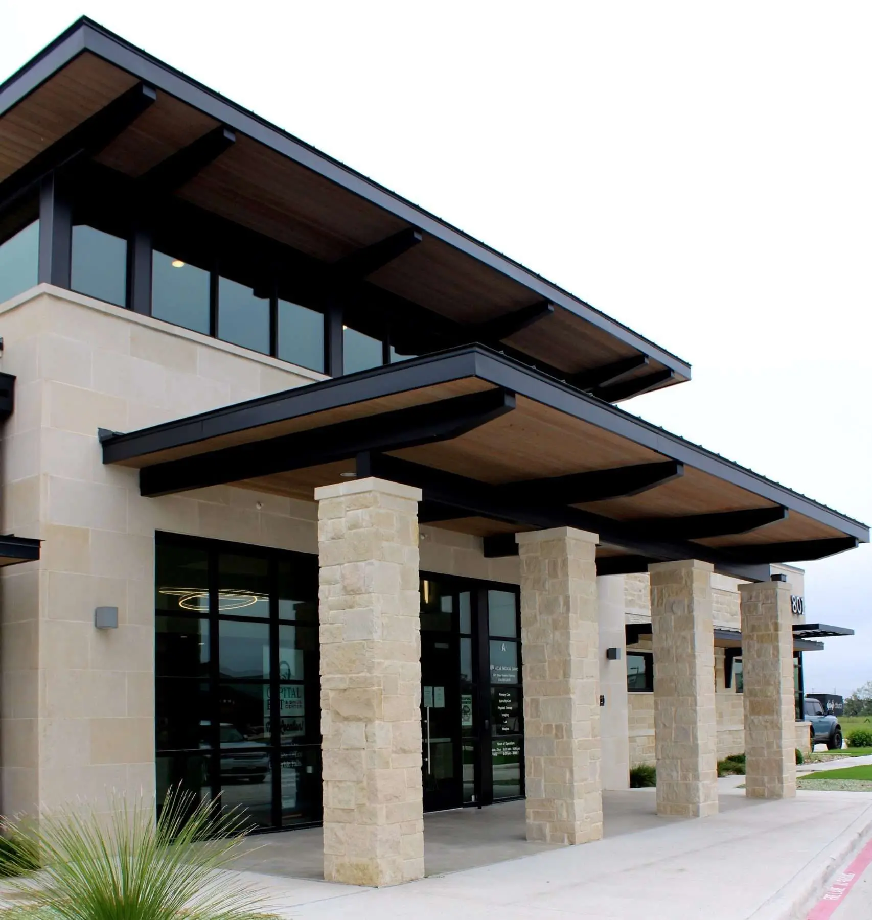 Modern stone commercial building entrance with a metal roof.