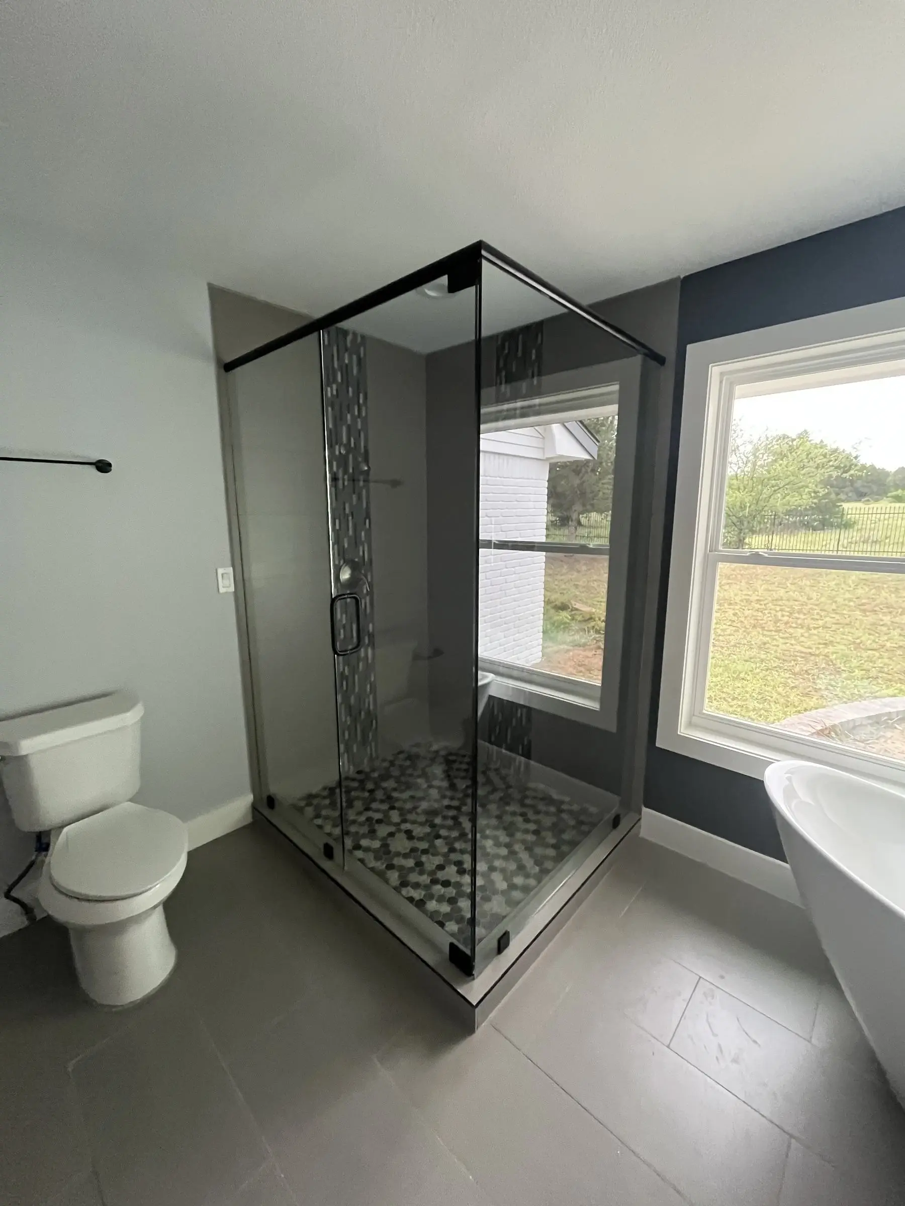 Neo-angle glass shower with a pebble-tile floor.