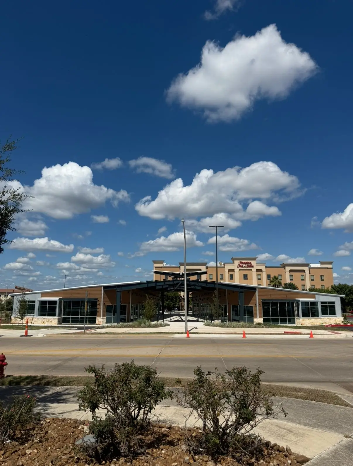 A newly finished retail building with continuous aluminum-framed storefront glazing above a limestone base.