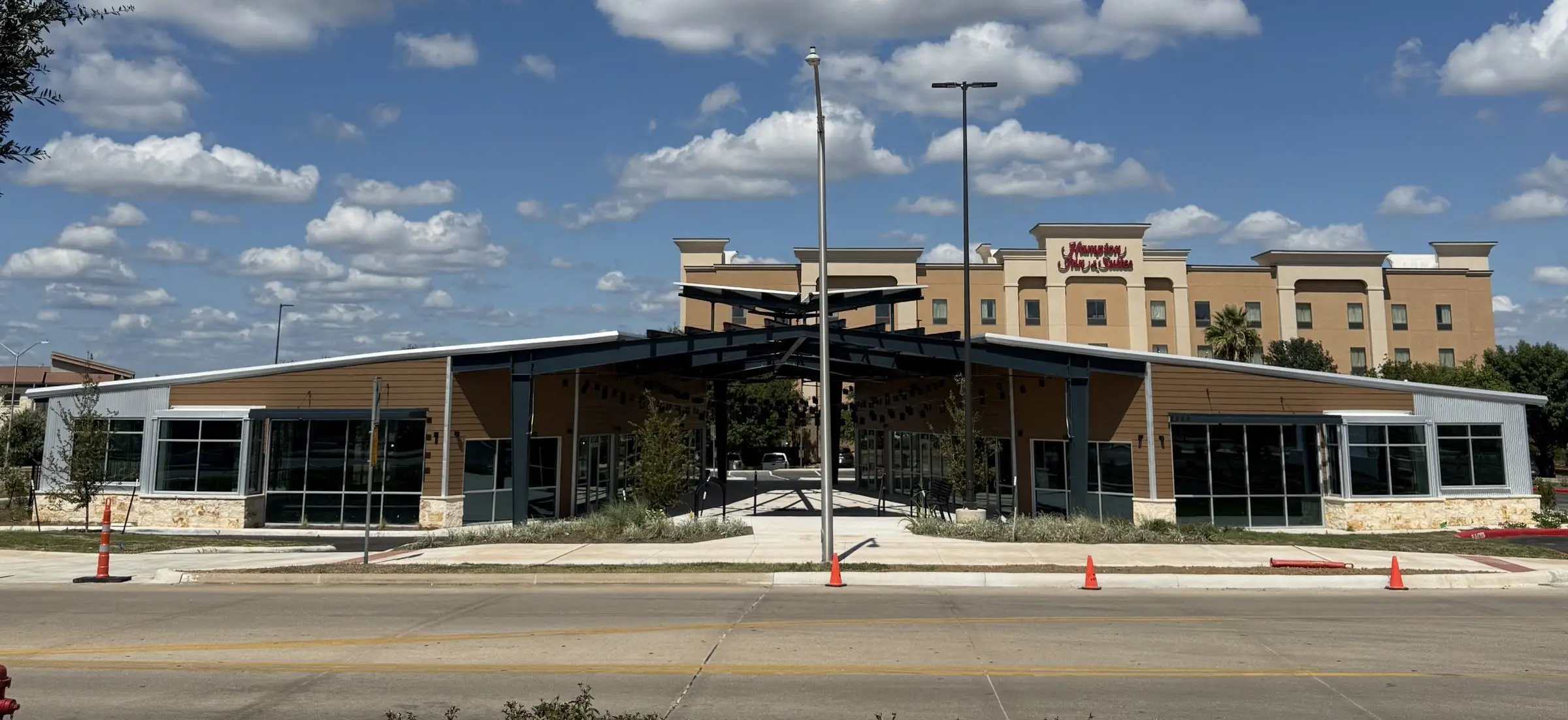 A single-story retail building with aluminum-framed storefront glazing wrapping both wings and a steel canopy over the central entry drive.